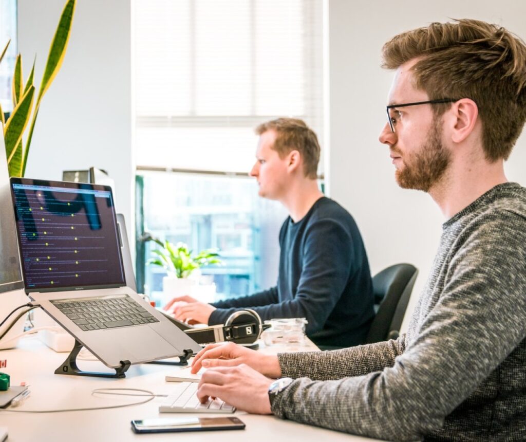 Dois homens trabalhando em computadores.